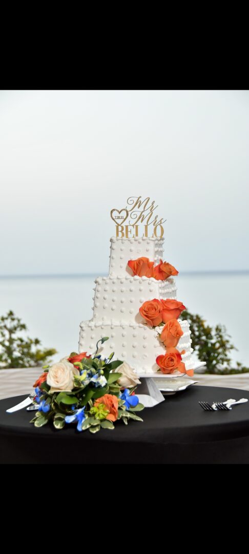 A white wedding cake with orange flowers on top.