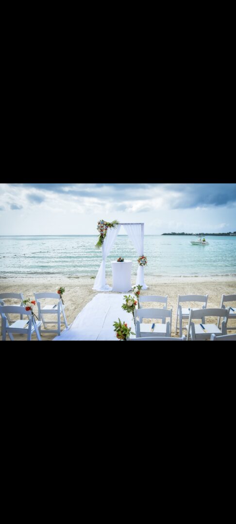 A beach wedding with chairs and tables on the sand