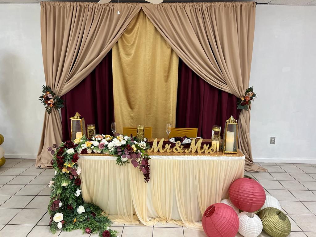 A table with flowers and candles in front of a curtain.