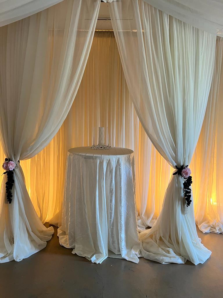 A room with white curtains and drapes on the walls.