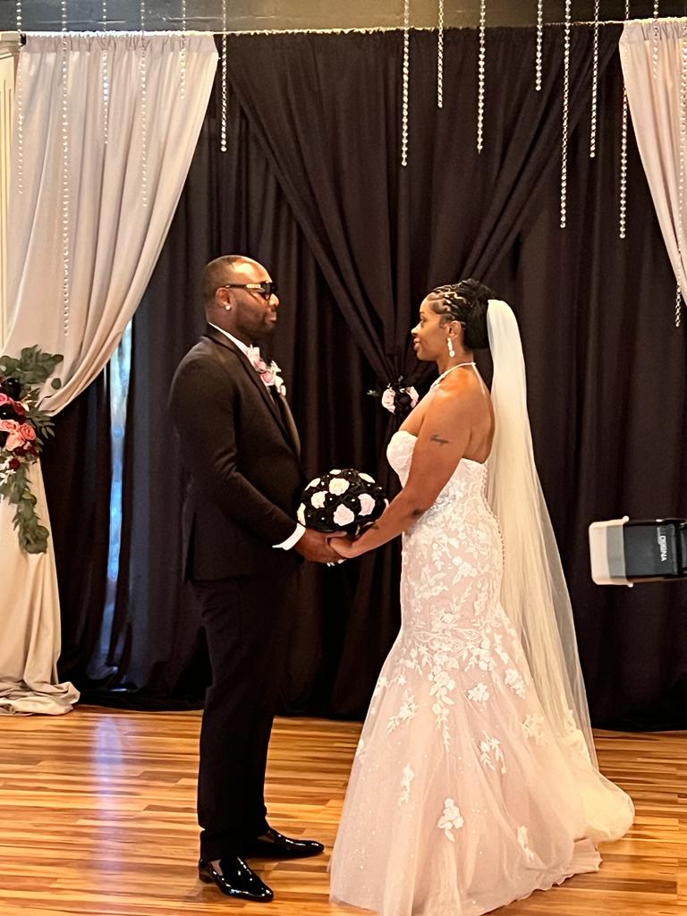 A bride and groom holding hands in front of the camera.
