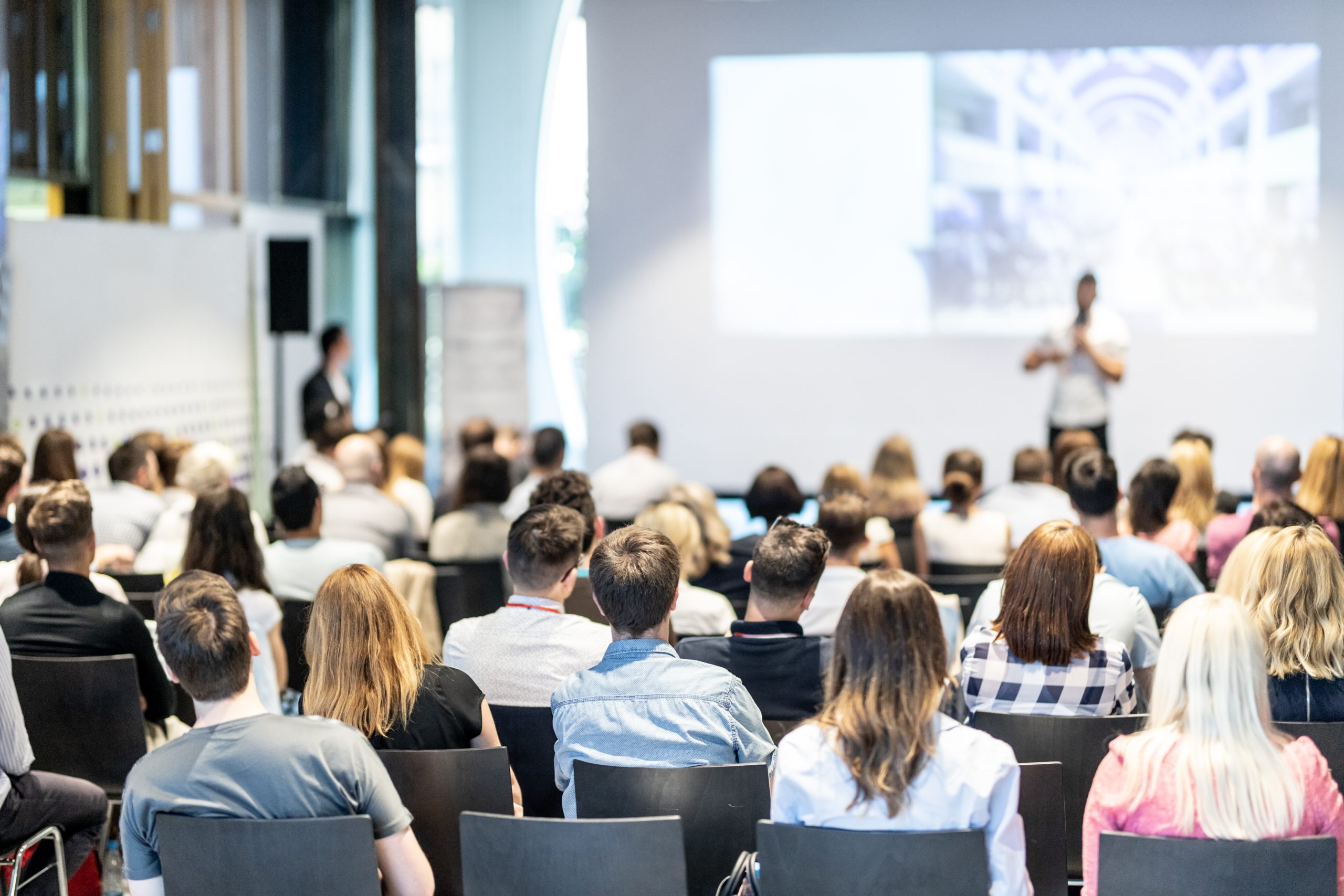 A group of people sitting in front of a projector screen.