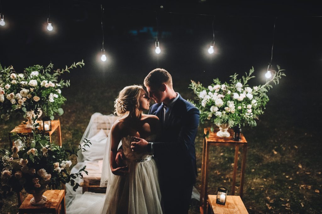 A man and woman kissing in front of lights.