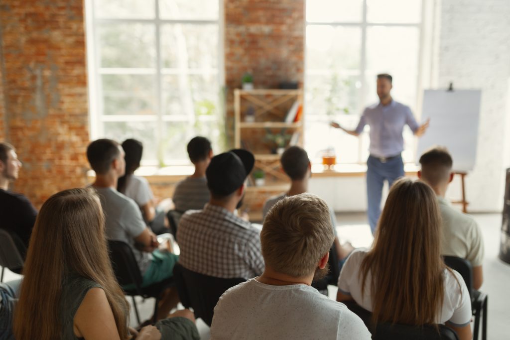 A group of people sitting in front of a man.