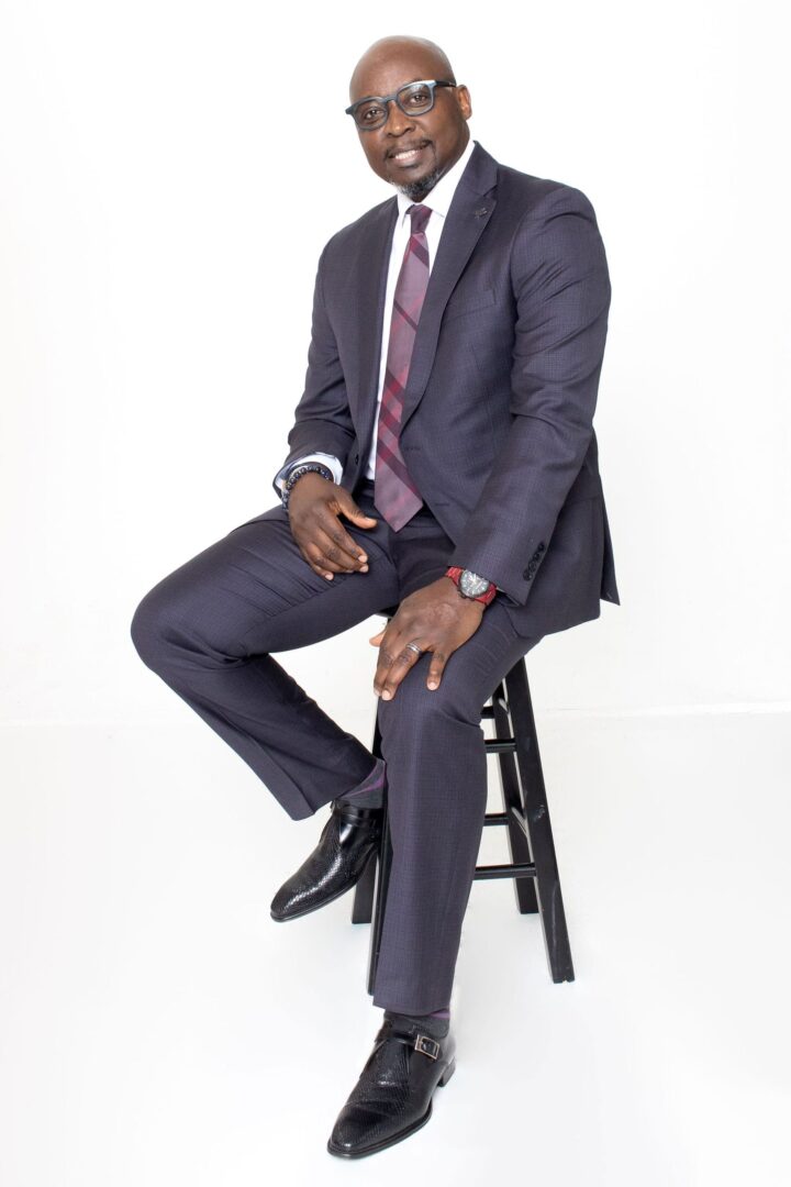 A man in a suit sitting on a stool