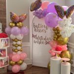 A balloon arch with balloons and butterflies.