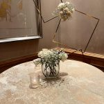 A table with flowers in it and a glass vase on top of the table.