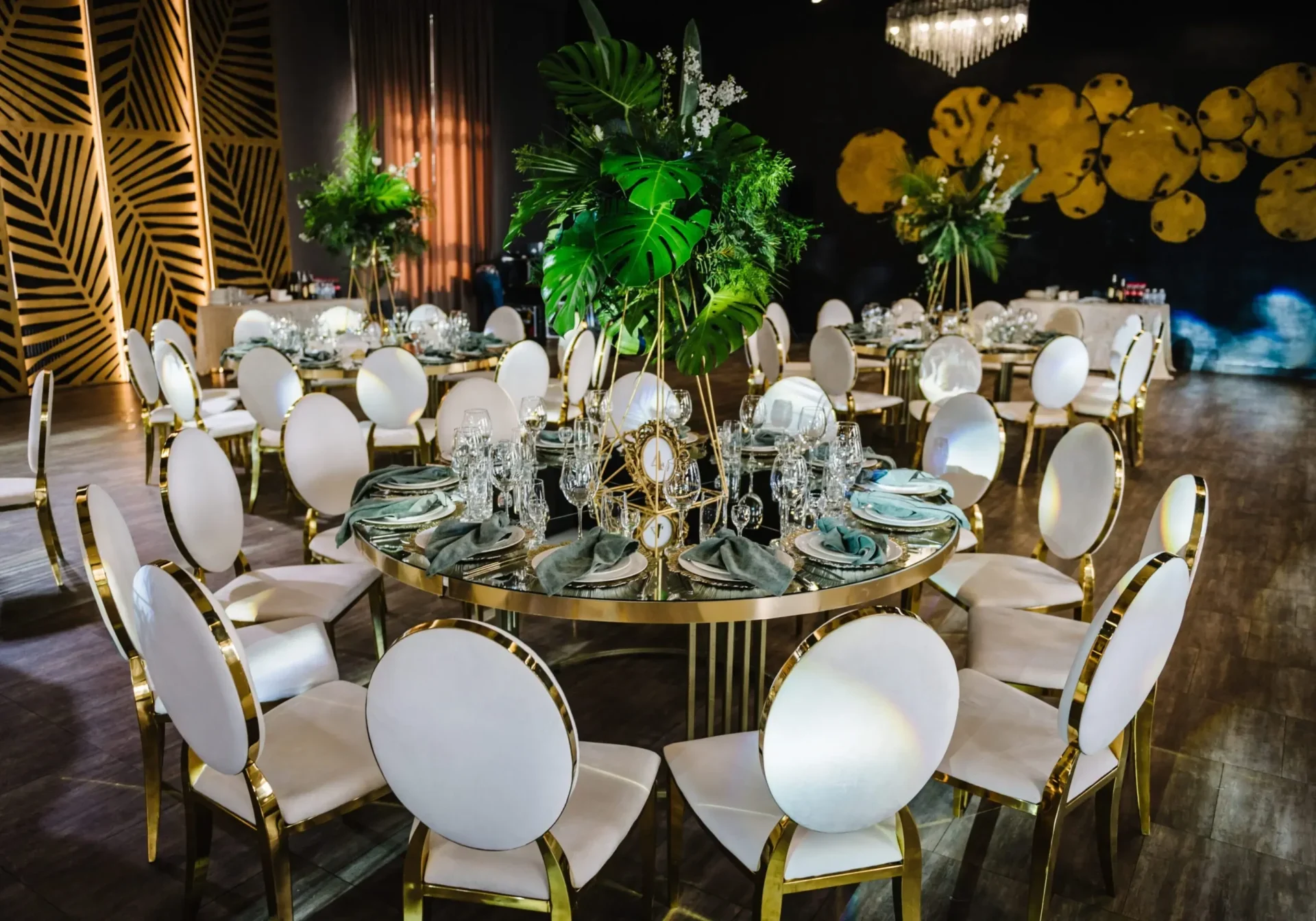 Elegant round table set for a formal event with white cushioned chairs and gold accents.
